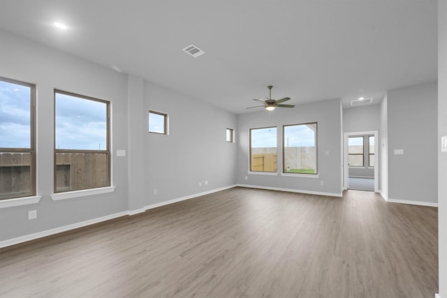 unfurnished living room featuring visible vents, baseboards, a ceiling fan, and wood finished floors
