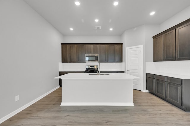 kitchen featuring tasteful backsplash, an island with sink, light countertops, visible vents, and stainless steel appliances