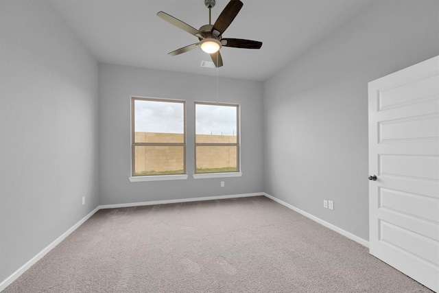 carpeted empty room featuring baseboards and a ceiling fan