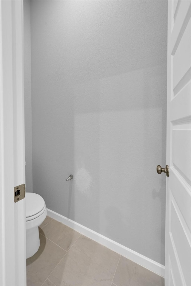 bathroom with toilet, tile patterned floors, and baseboards