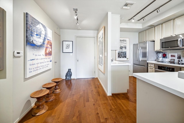 kitchen featuring light countertops, track lighting, stainless steel appliances, and visible vents