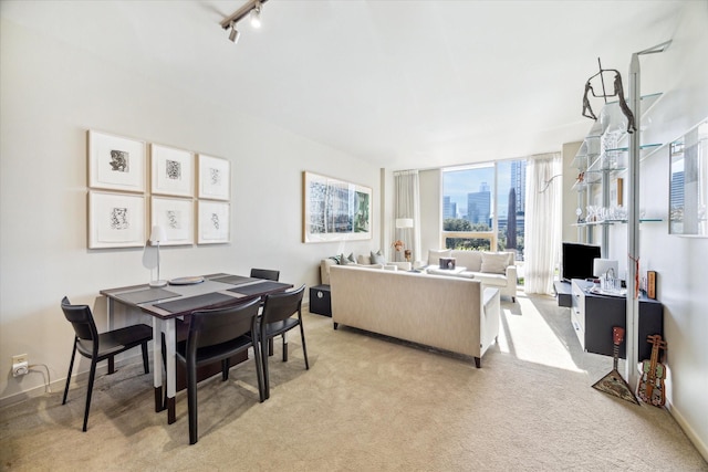 dining area with track lighting, expansive windows, and light colored carpet