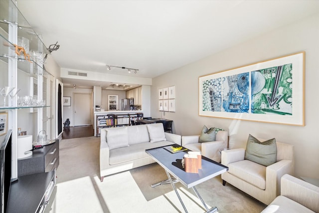 carpeted living area featuring rail lighting and visible vents