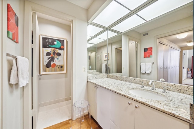 bathroom with wood finished floors, vanity, visible vents, and baseboards