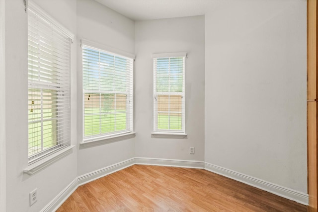 spare room featuring baseboards and wood finished floors