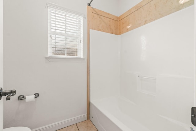bathroom featuring tile patterned floors, baseboards, toilet, and bathing tub / shower combination