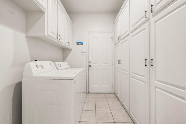laundry room with washing machine and clothes dryer, light tile patterned floors, and cabinet space
