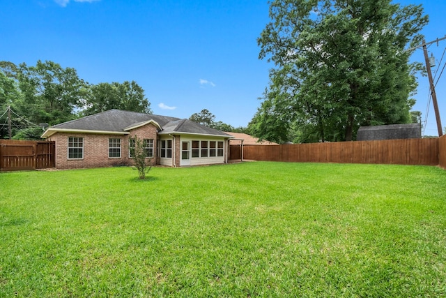 rear view of property with a yard and a fenced backyard