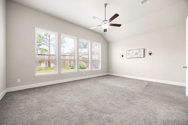 carpeted empty room with baseboards, lofted ceiling, ceiling fan, and visible vents