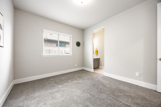 spare room with baseboards and light colored carpet