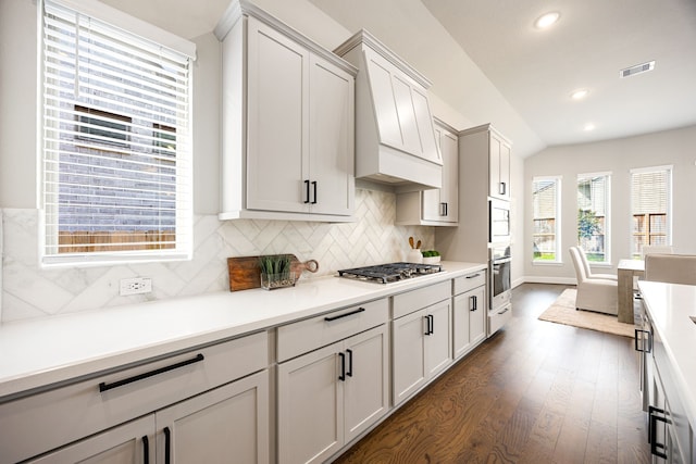 kitchen featuring light countertops, custom range hood, appliances with stainless steel finishes, visible vents, and decorative backsplash