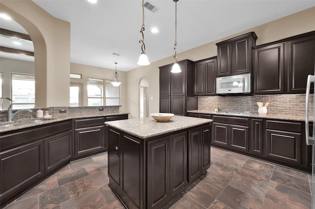 4510 Sanctuary Trails Dr, Spring, TX 77388 - kitchen featuring arched walkways, white microwave, a sink, decorative backsplash, and a center island