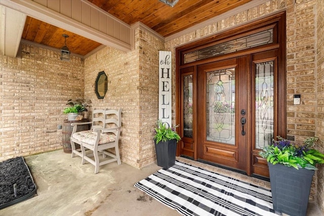 entrance to property featuring a porch and brick siding