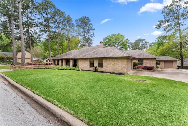 exterior space featuring a front lawn, a chimney, brick siding, a shingled roof, and driveway