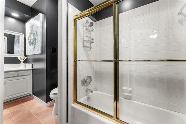 bathroom featuring tile patterned flooring, bath / shower combo with glass door, baseboards, vanity, and toilet