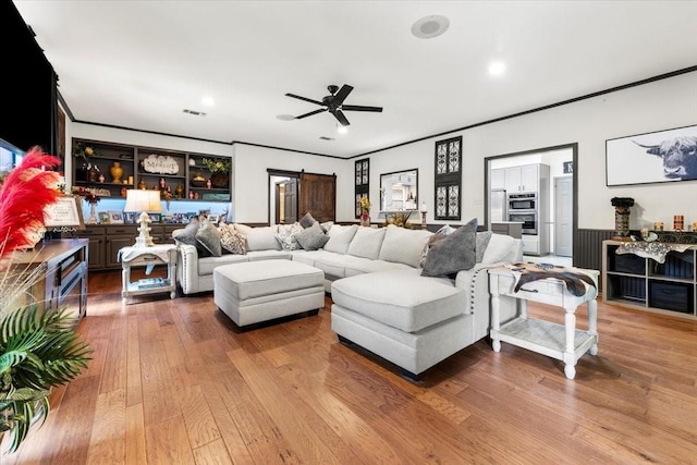 living room with crown molding, ceiling fan, wood finished floors, and visible vents