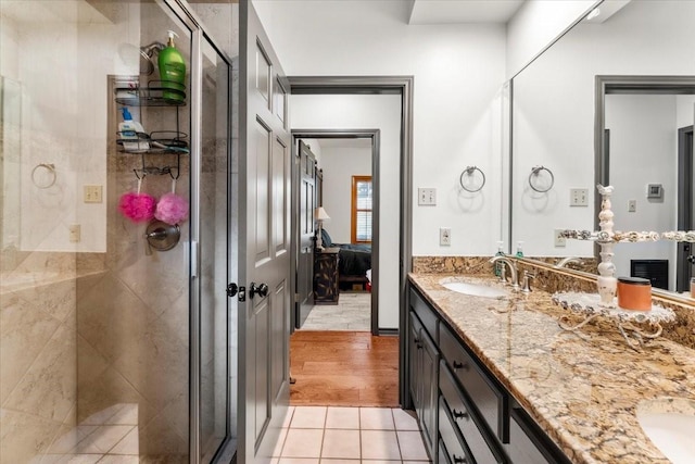 full bath featuring double vanity, a sink, a stall shower, and tile patterned floors