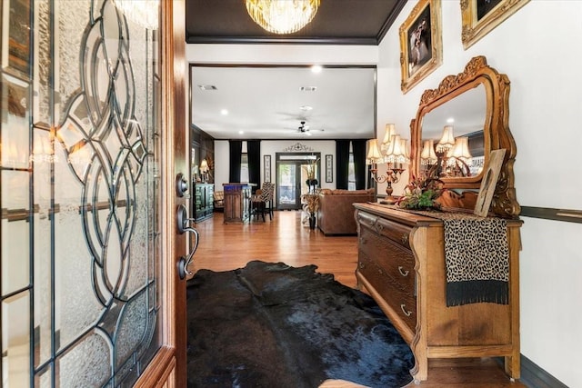 entryway featuring crown molding, ceiling fan with notable chandelier, and wood finished floors