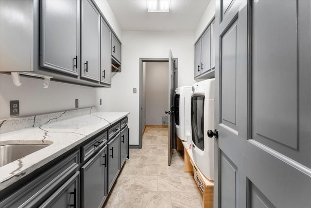 washroom with a sink, separate washer and dryer, cabinet space, and marble finish floor