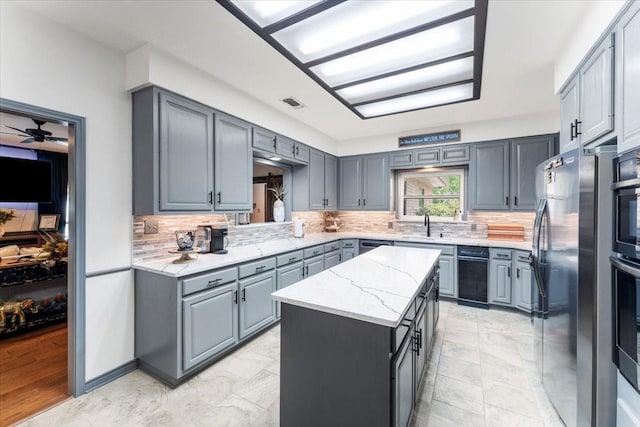 kitchen featuring appliances with stainless steel finishes, gray cabinets, a center island, and tasteful backsplash