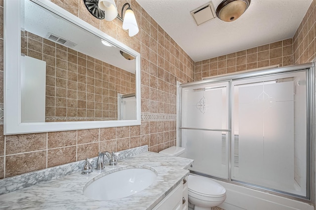 13322 Chaston Dr, Houston, TX 77041 - full bath with tile walls, toilet, vanity, combined bath / shower with glass door, and a textured ceiling