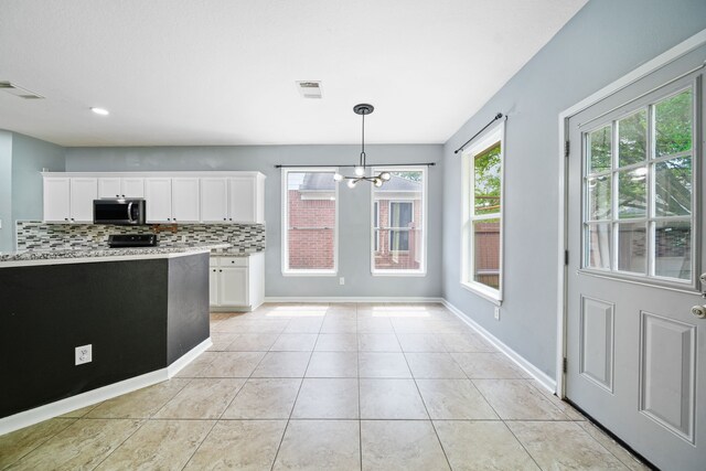 14507 Heron Marsh Dr, Cypress, TX 77429 - kitchen featuring stainless steel microwave, a chandelier, white cabinetry, and decorative backsplash