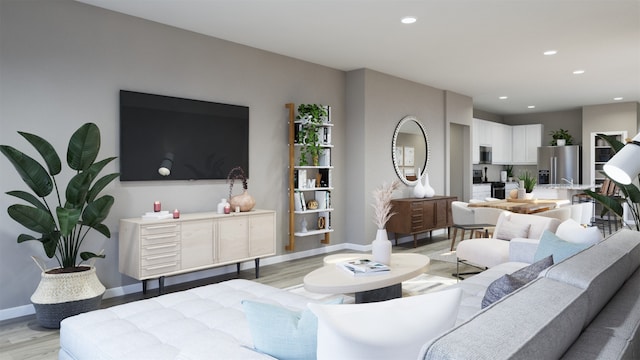 living room featuring baseboards, recessed lighting, and light wood finished floors