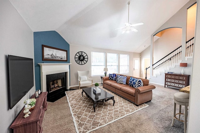 living room with ceiling fan, carpet, a fireplace with flush hearth, vaulted ceiling, and stairway