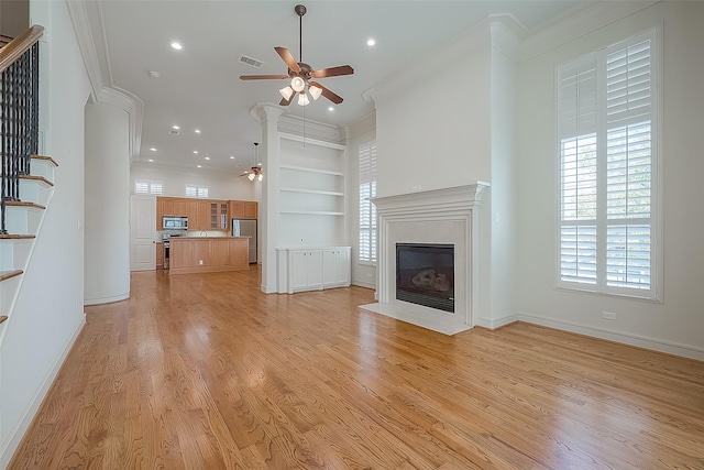 1804 Haddon St, Houston, TX 77019 - unfurnished living room featuring a ceiling fan, stairs, ornamental molding, a fireplace with flush hearth, and built in shelves
