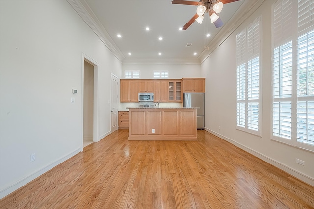 1804 Haddon St, Houston, TX 77019 - kitchen featuring appliances with stainless steel finishes, ornamental molding, a ceiling fan, a kitchen island with sink, and light wood finished floors