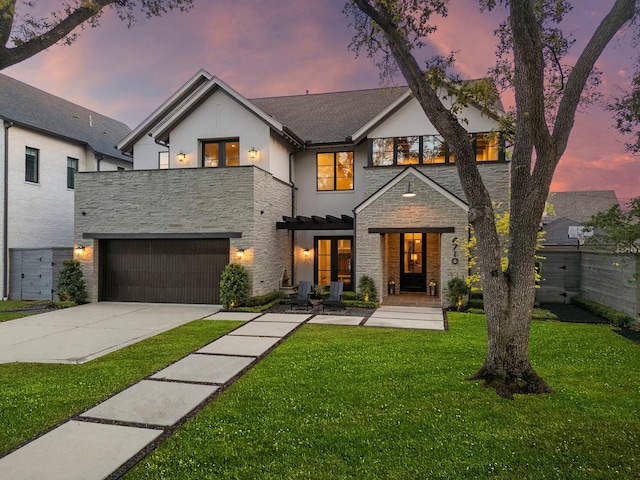 view of front of property featuring a yard, driveway, stone siding, french doors, and an attached garage
