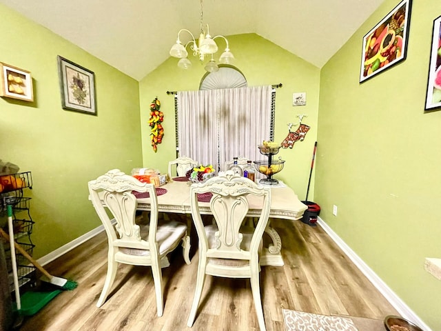 dining area featuring baseboards, lofted ceiling, wood finished floors, and a notable chandelier