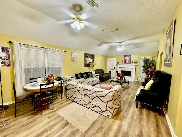 living room featuring visible vents, wood finished floors, ceiling fan, and a fireplace