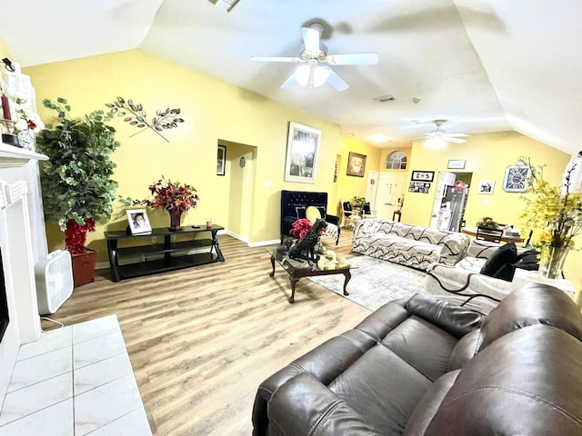 living room with light wood-style flooring, visible vents, vaulted ceiling, and ceiling fan