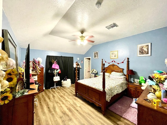 bedroom featuring a textured ceiling, lofted ceiling, light wood finished floors, and visible vents