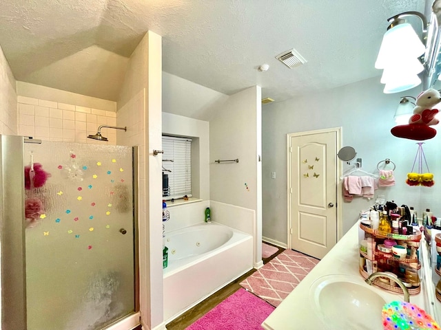 full bathroom featuring vanity, a shower stall, a tub with jets, a textured ceiling, and visible vents