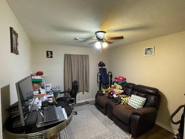 office space featuring a textured ceiling, baseboards, ceiling fan, and visible vents