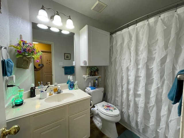 bathroom with vanity, toilet, a textured wall, visible vents, and curtained shower