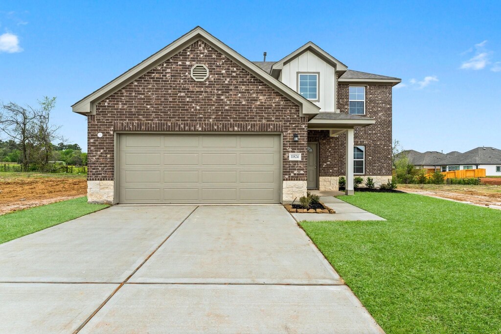 11824 Whirlaway Dr, Willis, TX 77318 - view of front facade featuring driveway, a front yard, a garage, and brick siding