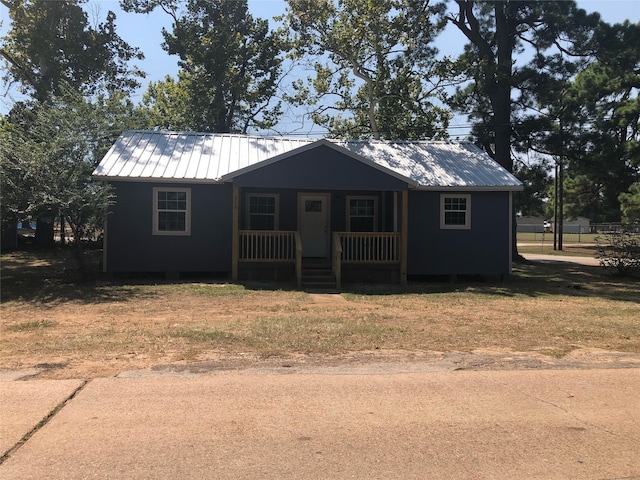 606 N Danville St, Willis, TX 77378 - view of front of house featuring covered porch, metal roof, and a front yard
