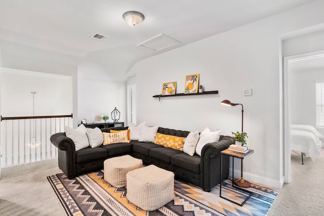 living area with visible vents, baseboards, attic access, carpet floors, and vaulted ceiling