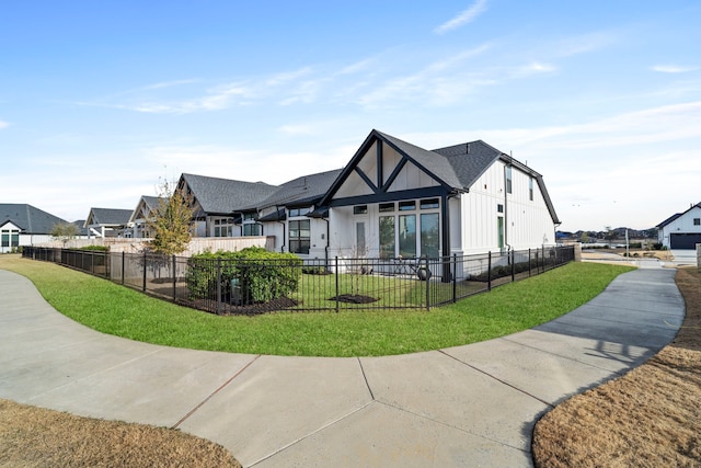 view of front of property featuring a fenced front yard, a front lawn, board and batten siding, and a residential view