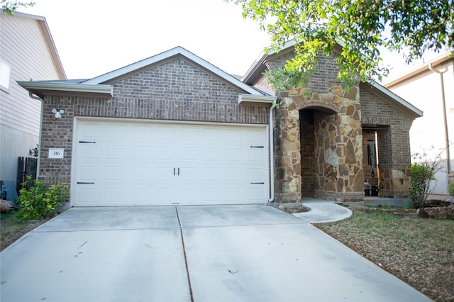 view of front of house with driveway, a garage, stone siding, and brick siding