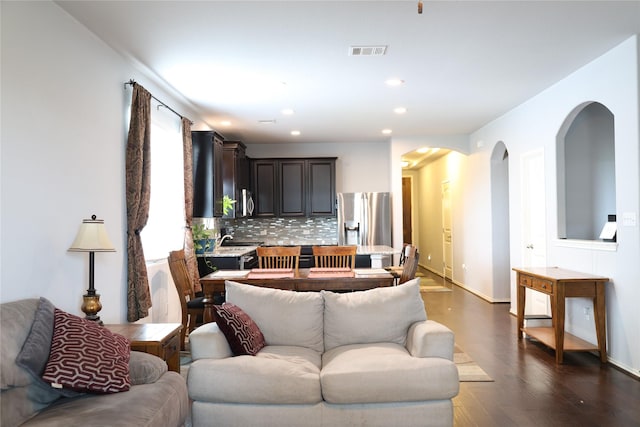 living area featuring dark wood-type flooring, arched walkways, recessed lighting, and baseboards