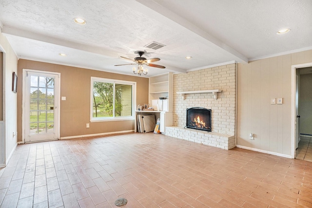 unfurnished living room featuring a textured ceiling, visible vents, a fireplace, a ceiling fan, and beam ceiling