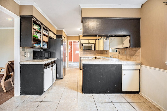 kitchen featuring light tile patterned floors, tile countertops, stainless steel appliances, and crown molding