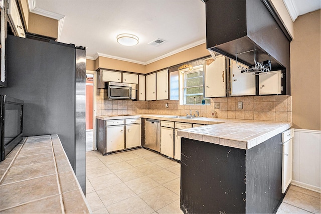 kitchen featuring visible vents, ornamental molding, tasteful backsplash, appliances with stainless steel finishes, and tile countertops