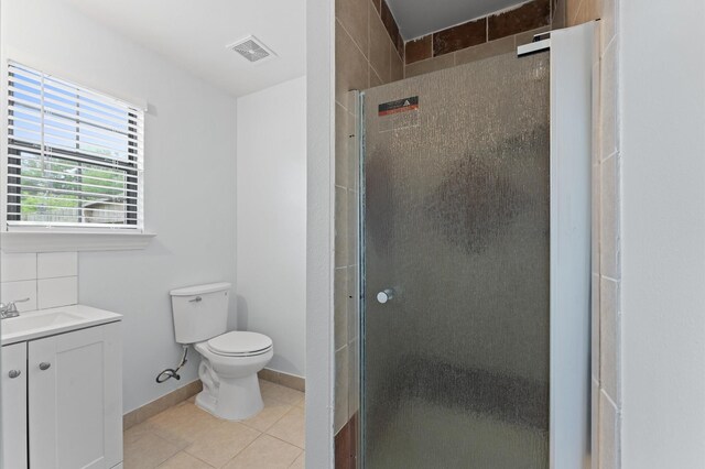 bathroom featuring tile patterned flooring, vanity, toilet, a shower stall, and visible vents