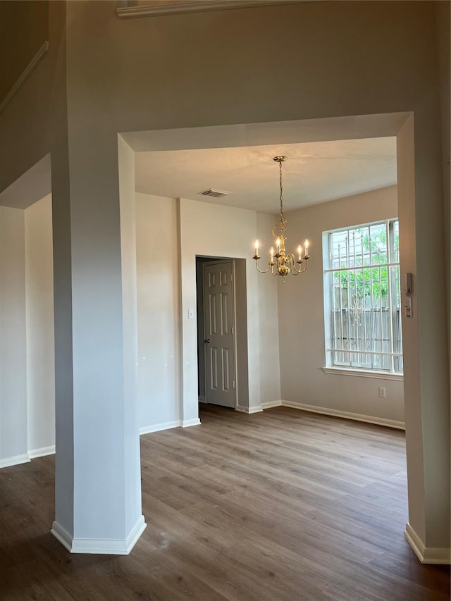 unfurnished dining area with dark wood-style flooring, baseboards, an inviting chandelier, and visible vents