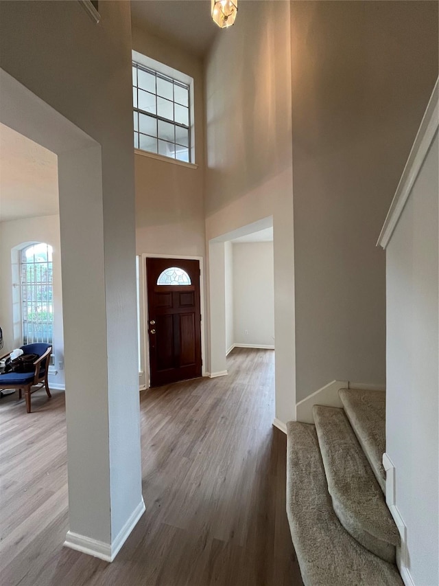 foyer entrance featuring wood finished floors, a high ceiling, baseboards, and stairs